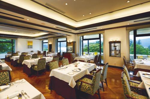 箱根小田急山之酒店(Odakyu Hotel de Yama)的用餐室设有桌椅和窗户。