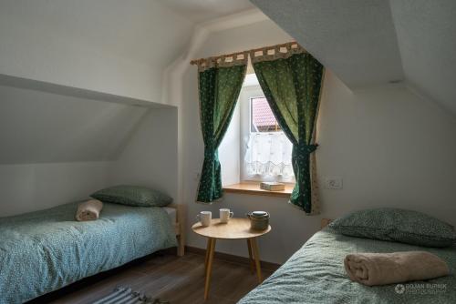 Stari Trg pri LožuCherry house - cosy house - ideal for bear watching, in the neighborhood of the medieval Snežnik castle的一间卧室设有两张床、一张桌子和一个窗口