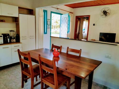 茹基蒂巴Casas de Campo Beija-Flor & Bem-Te-Vi, Mata Atlântica, Juquitiba, SP的厨房里一张木桌,上面有红色的花瓶