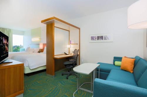 圣何塞圣何塞机场春季山丘套房酒店的酒店客房配有一张床、一张书桌和一张沙发。