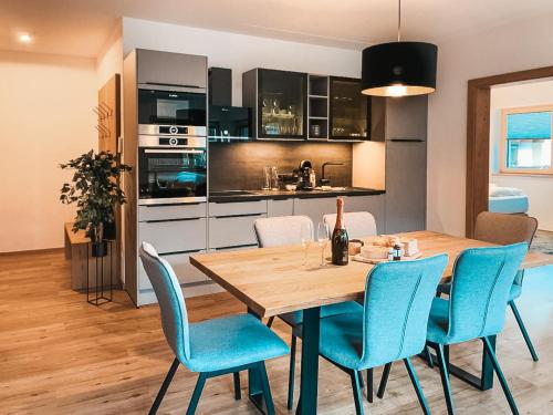菲根AlpenLuxus' RUHESTUBE with balcony & car park的厨房以及带木桌和蓝色椅子的用餐室。