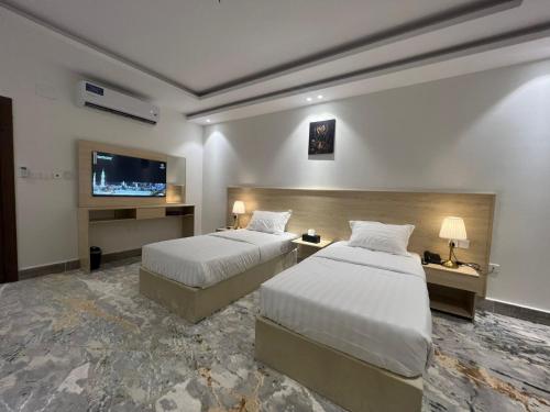 麦地那سويت إم للأجنحة الفندقية的酒店客房设有两张床和一台平面电视。