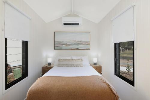 布伦瑞克黑兹Reflections Ferry Reserve - Holiday Park的一间卧室设有一张床和两个窗户。