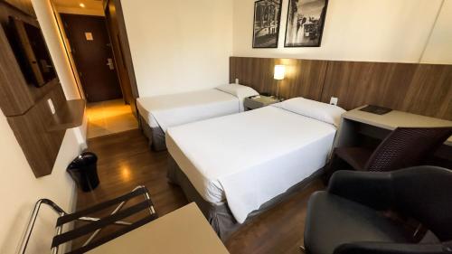 贝洛奥里藏特Hotel Vivenzo Savassi Belo Horizonte的酒店客房 - 带两张床、一张桌子和一把椅子