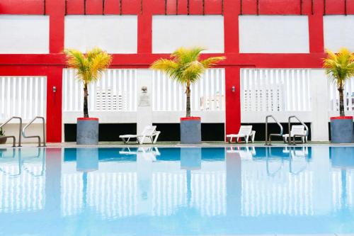 马六甲Hotel Sentral Melaka @ City Centre的一座建筑前的游泳池,里面设有椅子和棕榈树