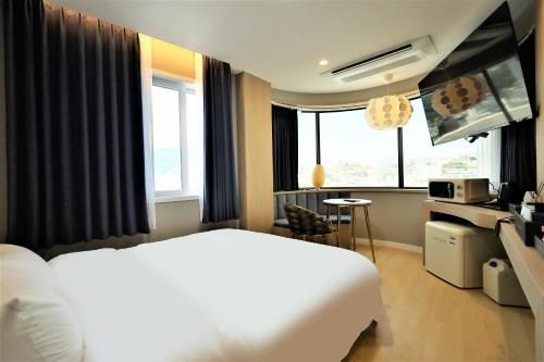 统营市De Lamour Hotel的酒店客房设有白色的床和窗户。
