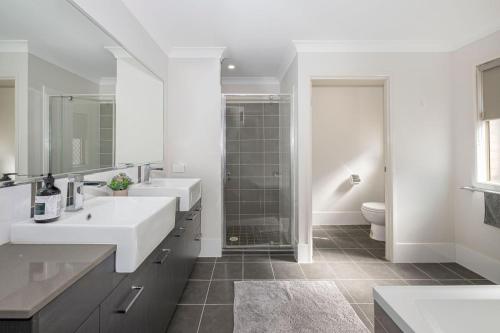 布里斯班Large house 7 mins from Airport的白色的浴室设有2个盥洗盆和淋浴。