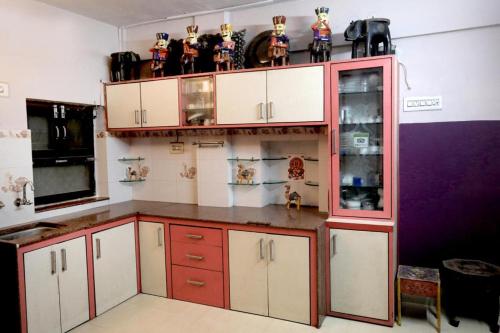 焦特布尔Banasa Heritage Haveli的厨房配有红色和白色的橱柜,上面有雕像