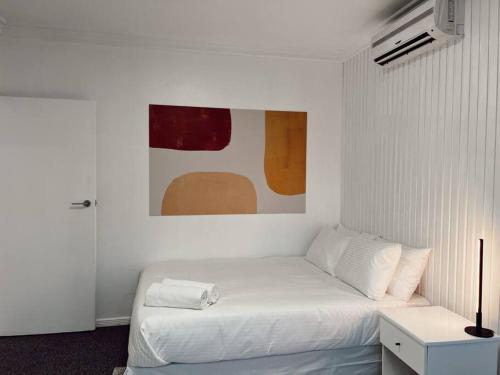 苏瓦Gem 7 Gladstone Apts - Suva CBD 2bdrm的白色卧室配有一张床,墙上挂着一幅画