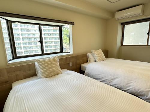 热海热海美景私人温泉公寓式酒店的带2扇窗户的小客房内的2张床
