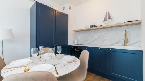 斯图托沃Apartamenty Sun & Snow Baltic Twins的厨房配有蓝色橱柜和酒杯桌子