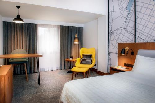 阿布扎比阿布扎比艾美假村酒店的酒店客房配有一张床、一张黄色椅子和一张书桌