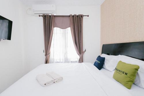DauUrbanview Hotel Sultan Palace Malang by RedDoorz的卧室配有白色的床和窗户