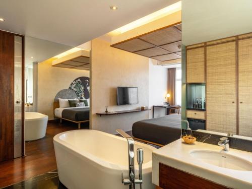 塞米亚克The Isvara by Cove的酒店客房设有浴缸和卧室。