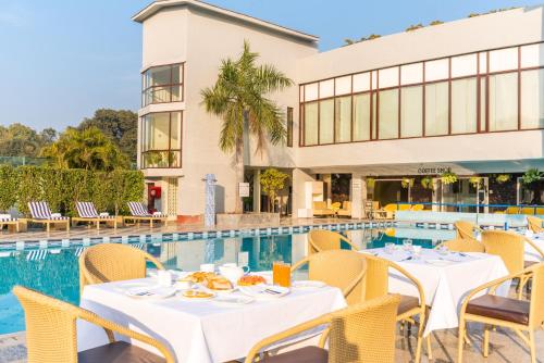 古尔冈Best Western Resort Country Club的游泳池旁的餐厅配有桌椅