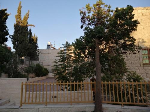 希伯仑Lamar Guesthouse - Hebron的建筑前有树的木栅栏