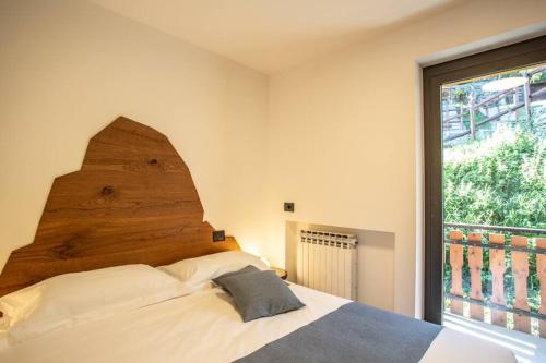 沙穆瓦La Rosa delle Alpi Luxury Apartment的一间卧室配有一张带木制床头板的床和窗户。