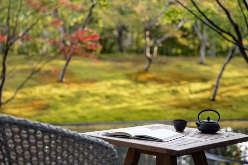 京都Garrya Nijo Castle Kyoto - Banyan Group的一张木桌,上面有书和茶壶