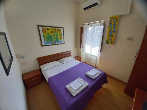 罗马Casa Campo de' Fiori的一间卧室配有一张带紫色毯子的床