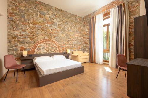 佛罗伦萨贝坦尼亚别墅酒店的一间卧室设有砖墙、一张床和椅子
