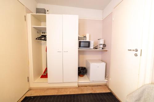 卡拉约基Rantakallan Rinne rivitalohuoneet的一间小客房内的白色橱柜,配有微波炉