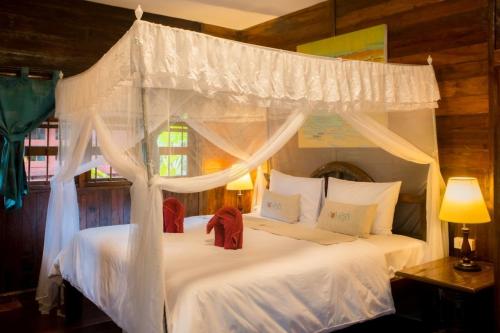 Ban Cha-omCountry Cafe & Camping的一间卧室配有两张带白色床单和天蓬的床。