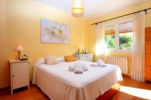 坎帕斯蒂利亚Bonito chalet con piscina cerca del mar的一间卧室配有一张带白色床单的床和一扇窗户。