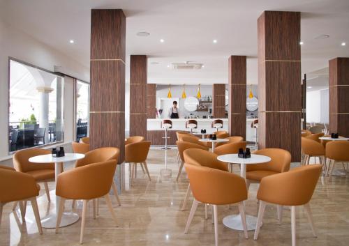 拉曼加戴尔马尔梅纳海豚酒店的一间设有白色桌子和橙色椅子的餐厅