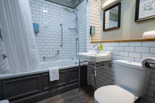 圣伦纳兹St Leonards Hotel by Greene King Inns的一间带水槽、浴缸和卫生间的浴室