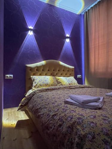 卡兹贝吉Sunny guesthouse的一间卧室配有一张紫色墙壁和灯床