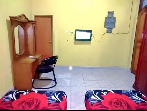 RambahHotel Garuda的一间房间,配有椅子、电视和玫瑰