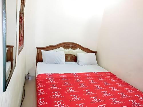 RambahHotel Garuda的一间卧室配有一张带红色毯子的床