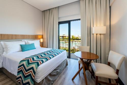 卡布雷乌瓦Japy Golf Resort Hotel的一间卧室配有一张床、一张桌子和一个窗户。