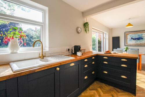 诺丁汉Elegant 3-Bed Home, West Bridgford & Large Garden的厨房配有黑色橱柜、水槽和窗户。