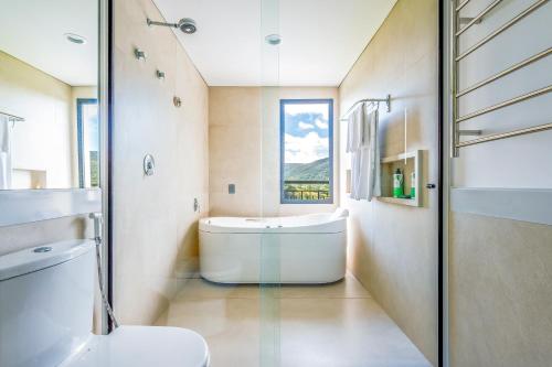 卡布雷乌瓦Japy Golf Resort Hotel的带浴缸、卫生间和窗户的浴室