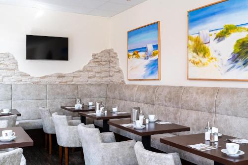 威廉港Hotel Banter Hof的餐厅设有桌椅和平面电视。