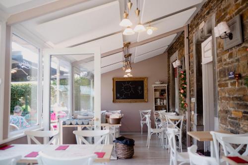 Annevoie-RouillonLogis Le P'tit Rouillon au Rythme de la Meuse的一间设有白色桌椅的餐厅,以及砖墙