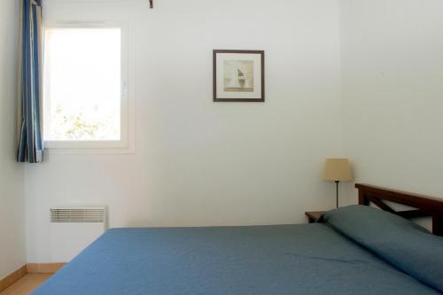 卡罗Résidence Goélia Cap Bleu的一间卧室设有蓝色的床和窗户。
