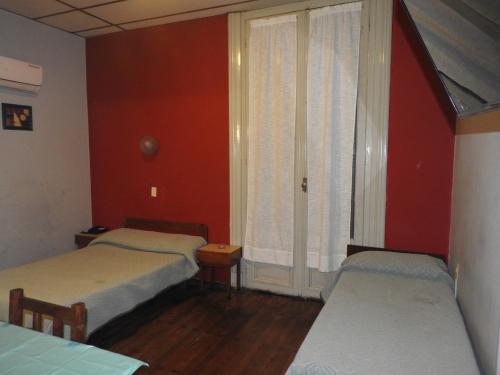 蒙得维的亚Hotel Ideal的宿舍间的两张床,设有红色的墙壁和窗户。