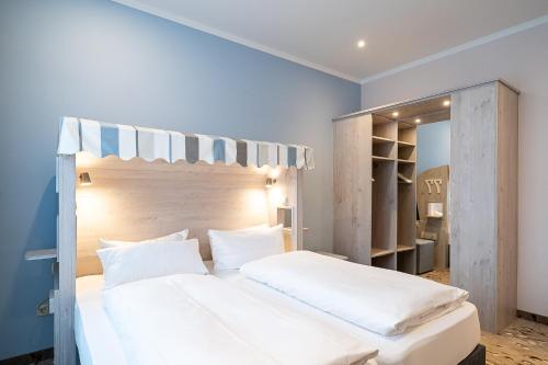 威廉港Wilhelms HAVEN HOTEL的卧室配有一张白色大床和镜子