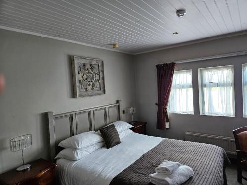 哈德斯菲尔德Pennine Manor Hotel的一间卧室设有一张床和两个窗户。