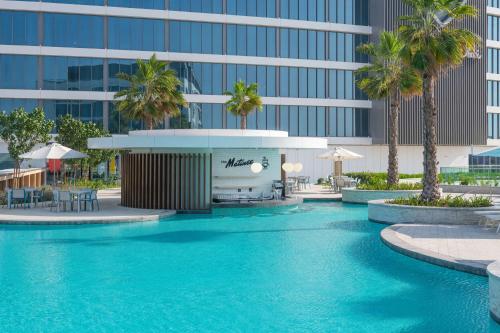 阿布扎比The WB Abu Dhabi, Curio Collection By Hilton的棕榈树建筑前的游泳池