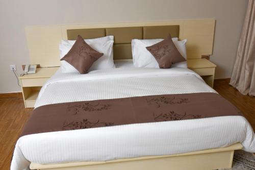 MasakaHotel Next的一张大床,配有棕色和白色的床单和枕头