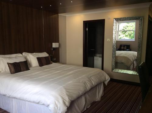 BurscoughBriars Hall Hotel的卧室配有一张白色大床和镜子