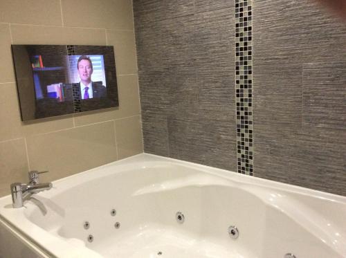BurscoughBriars Hall Hotel的浴室设有浴缸、电视和