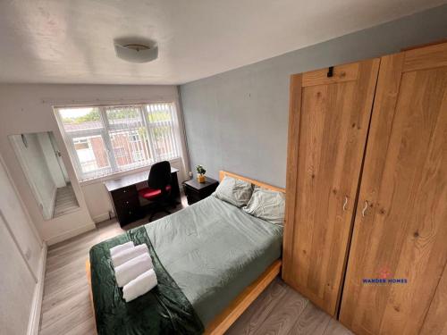 伯明翰Ensuite Rooms Birmingham Underwood Close的一间卧室配有一张床和一个木制橱柜