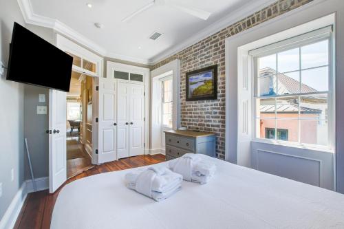 查尔斯顿Rainbow Row Pied-A-Terre的卧室配有白色的床和窗户。