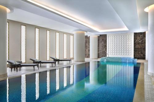 利雅德Hilton Riyadh Hotel & Residences的大楼内一个带桌椅的游泳池