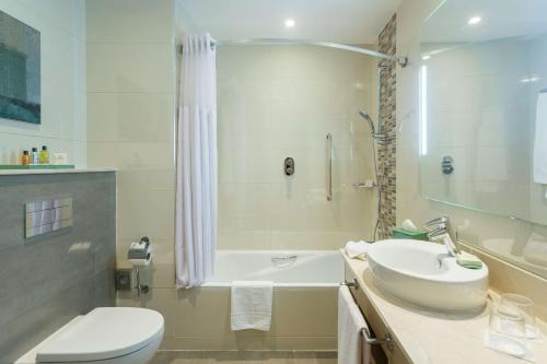 丹吉尔丹吉尔市中心希尔顿花园酒店的浴室配有盥洗盆、卫生间和浴缸。