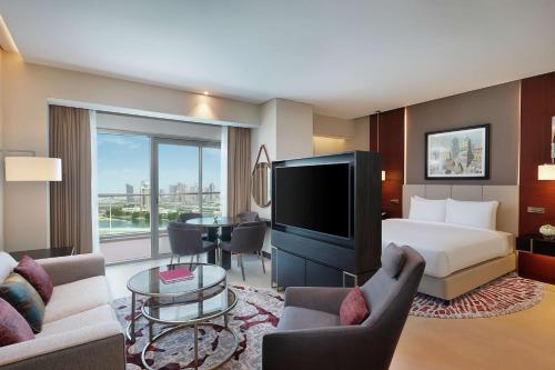 多哈Hilton Doha The Pearl的酒店客房设有一张床、一台电视和一间卧室。